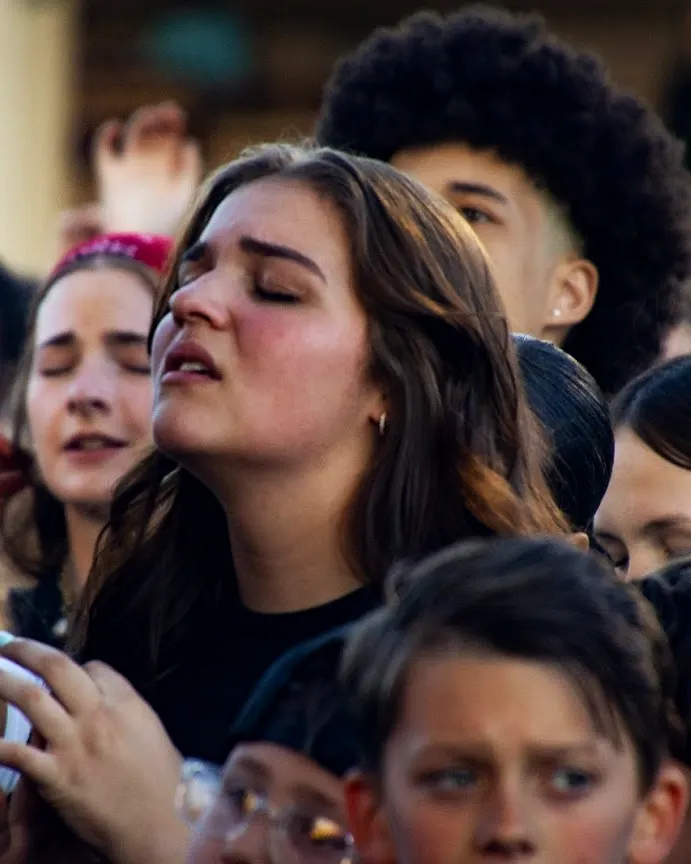 A student worshiping with her eyes closed