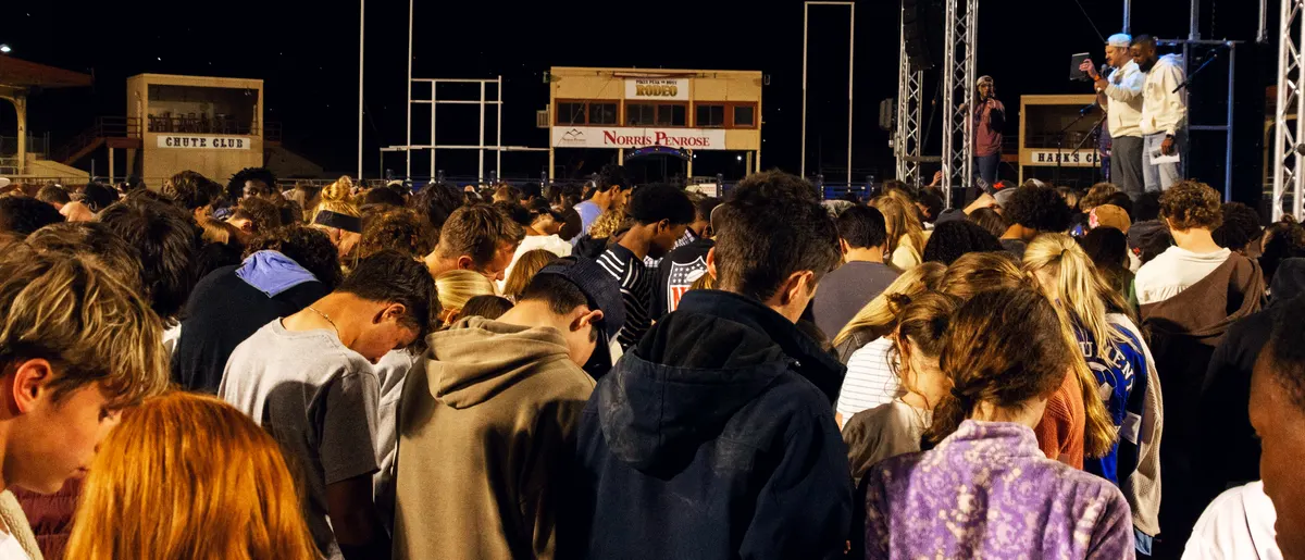 Students bowing their heads in prayer during the night